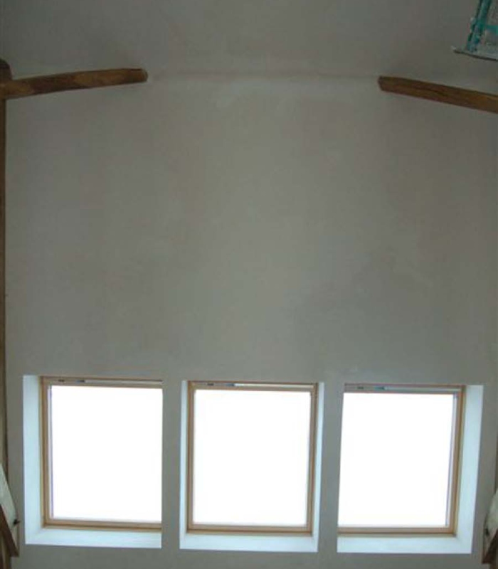 Mur intérieur peint avec finition lisse et intégration de fenêtres de toit apportant une lumière naturelle