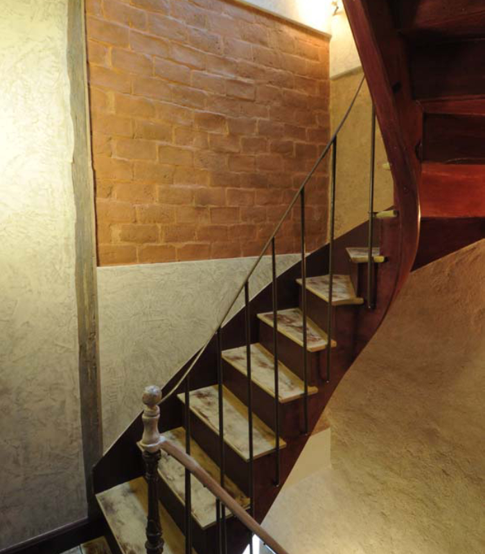 Escalier intérieur avec mur en briques apparentes, enduits décoratifs et finitions peintes soignées